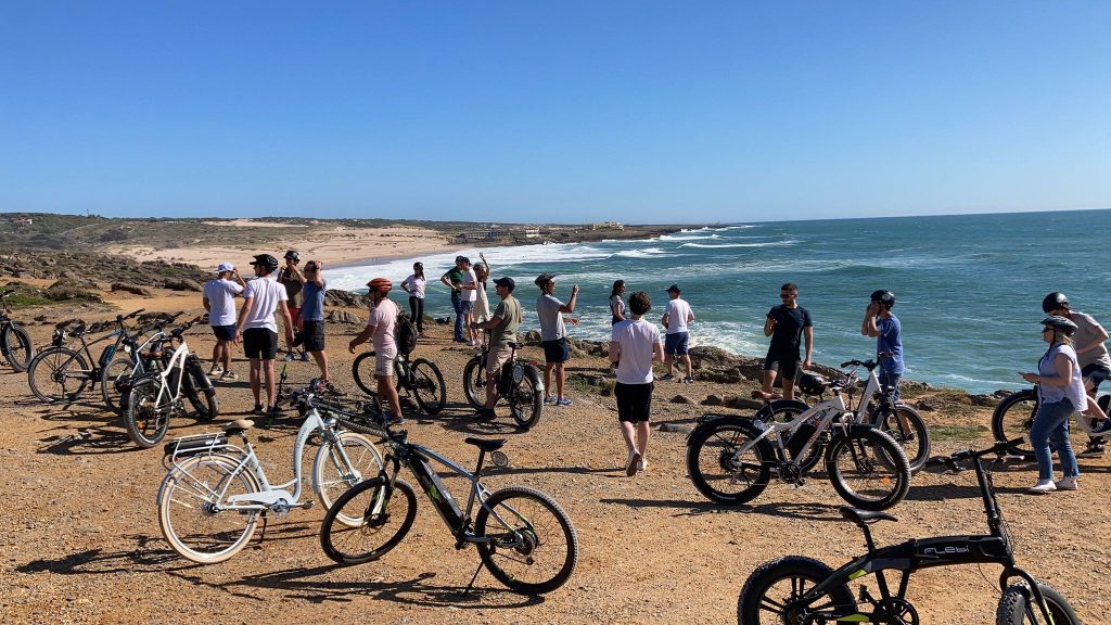 A_diverse_group_of_people_doing_team_building_activity_ebike_beach_guincho_in_cascais