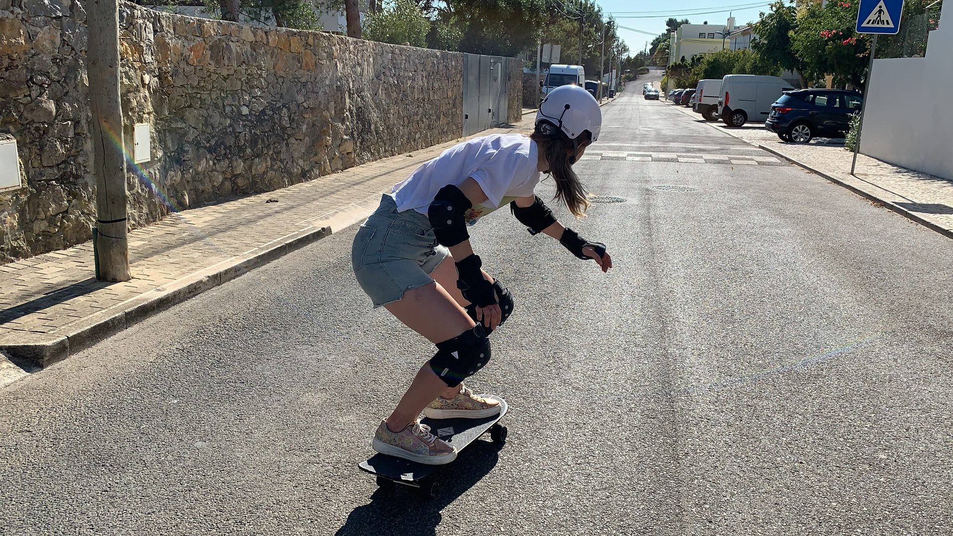 A student bombing a longboard down an open road through the Sintra hills, arms wide and grinning