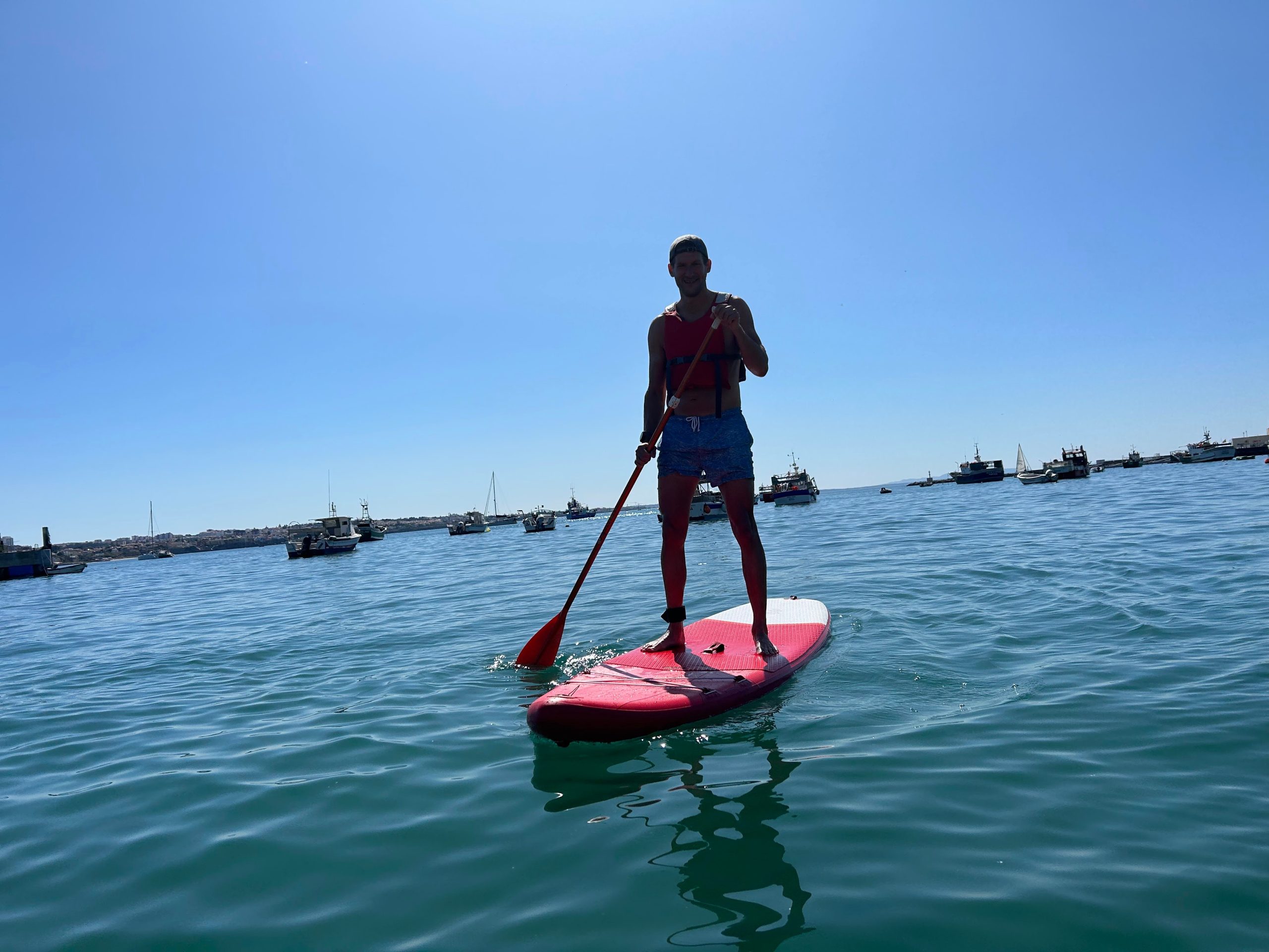 Man paddling a stand-up paddleboard in Cascais harbor