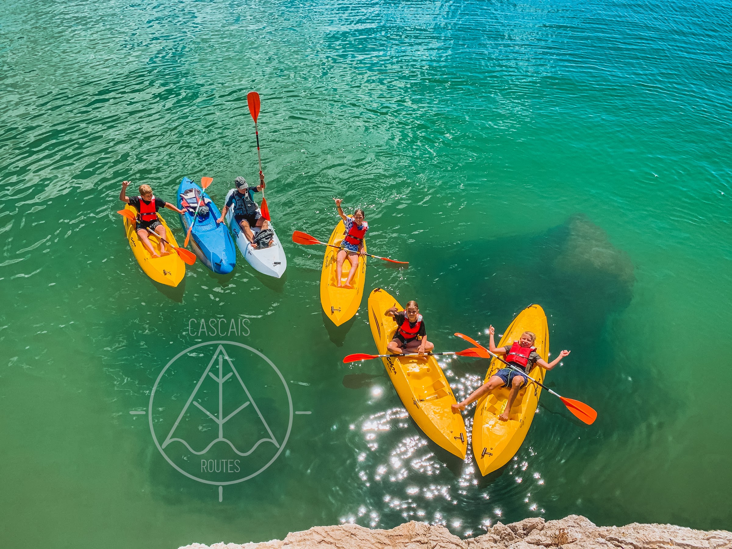 Kids paddling kayaks on turquoise water