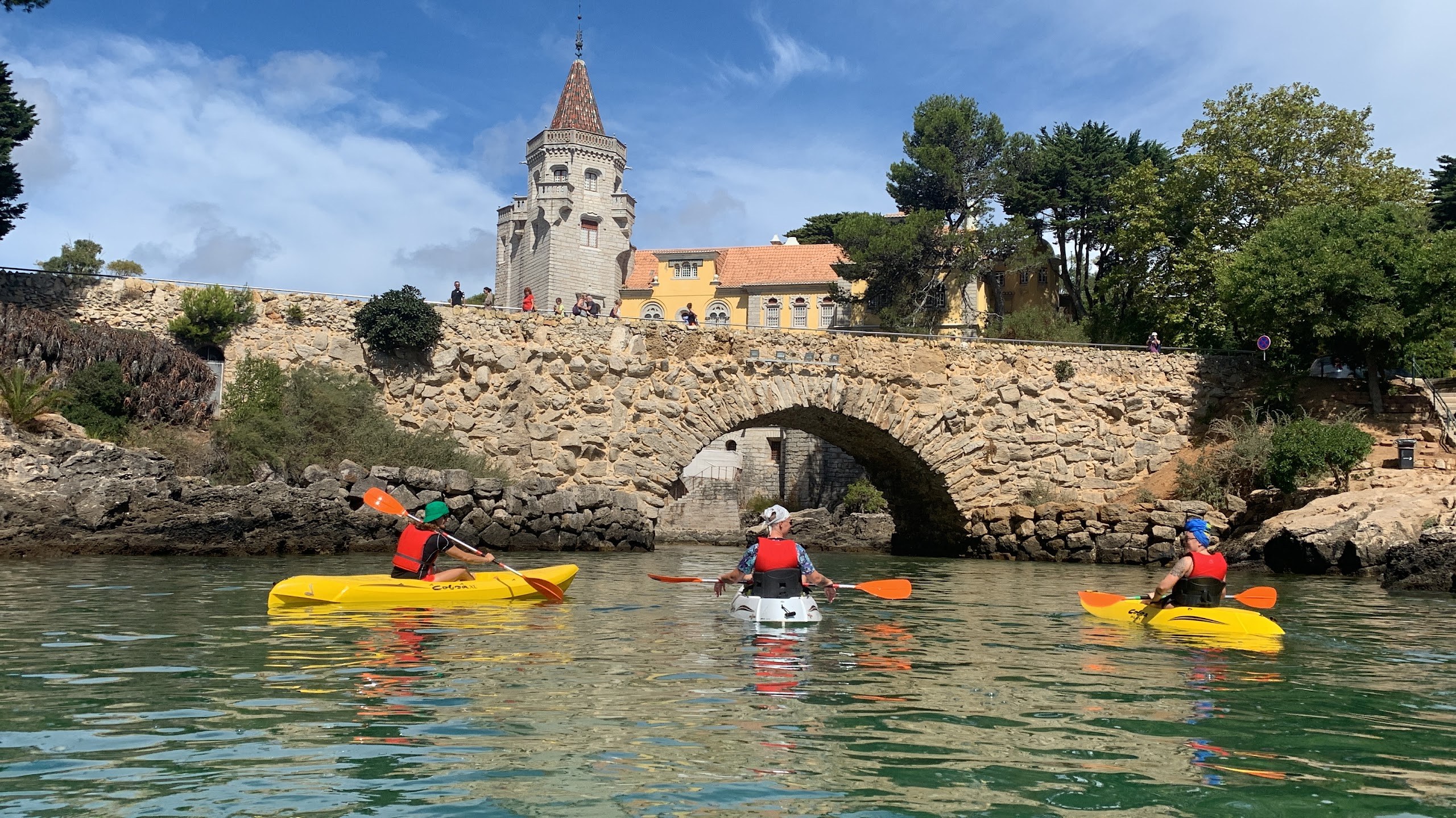 Kayakers paddling under a stone bridge near the Cidadela, Cascais