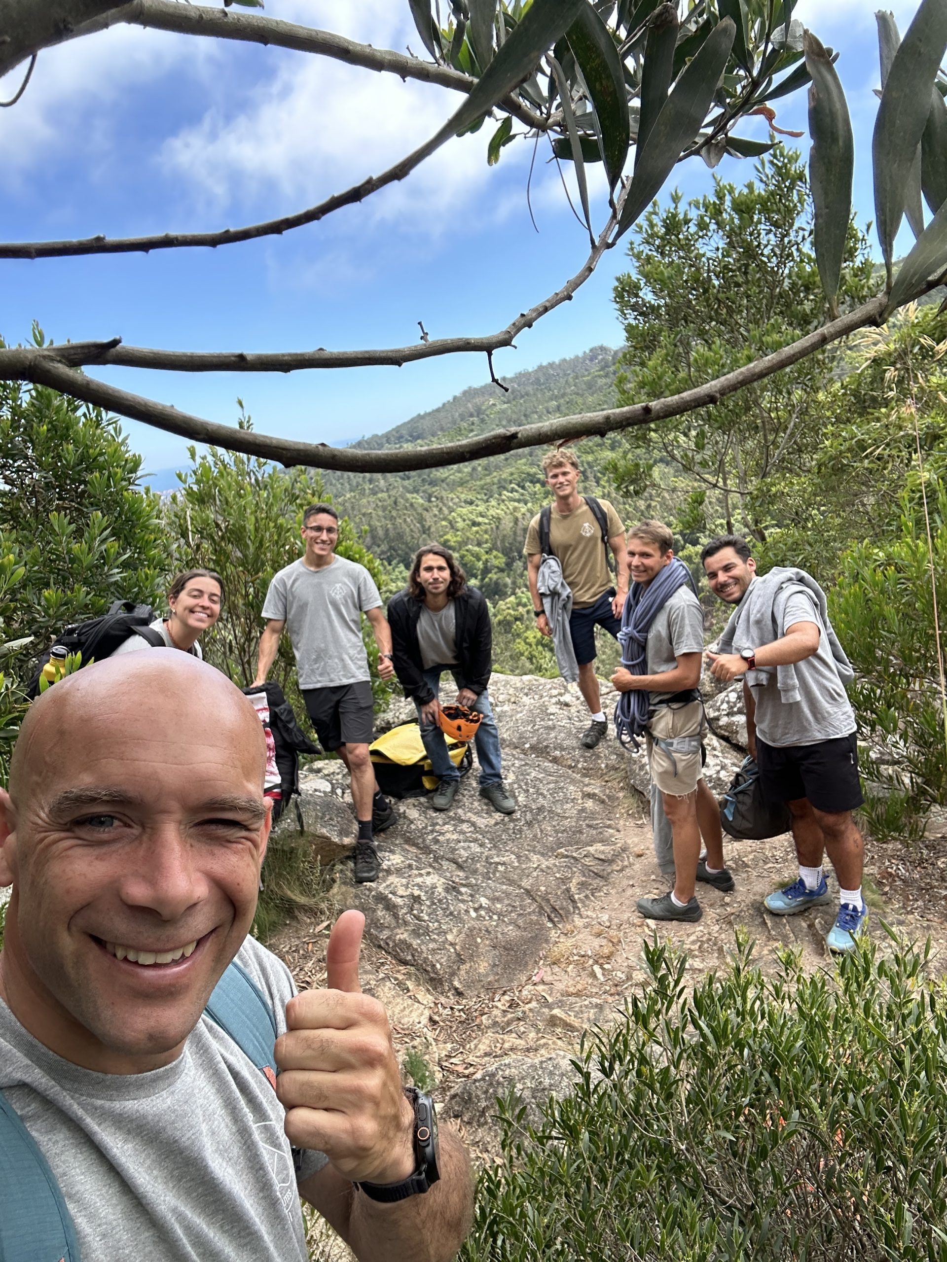 Hiking group with climbing gear posing on a rocky summit