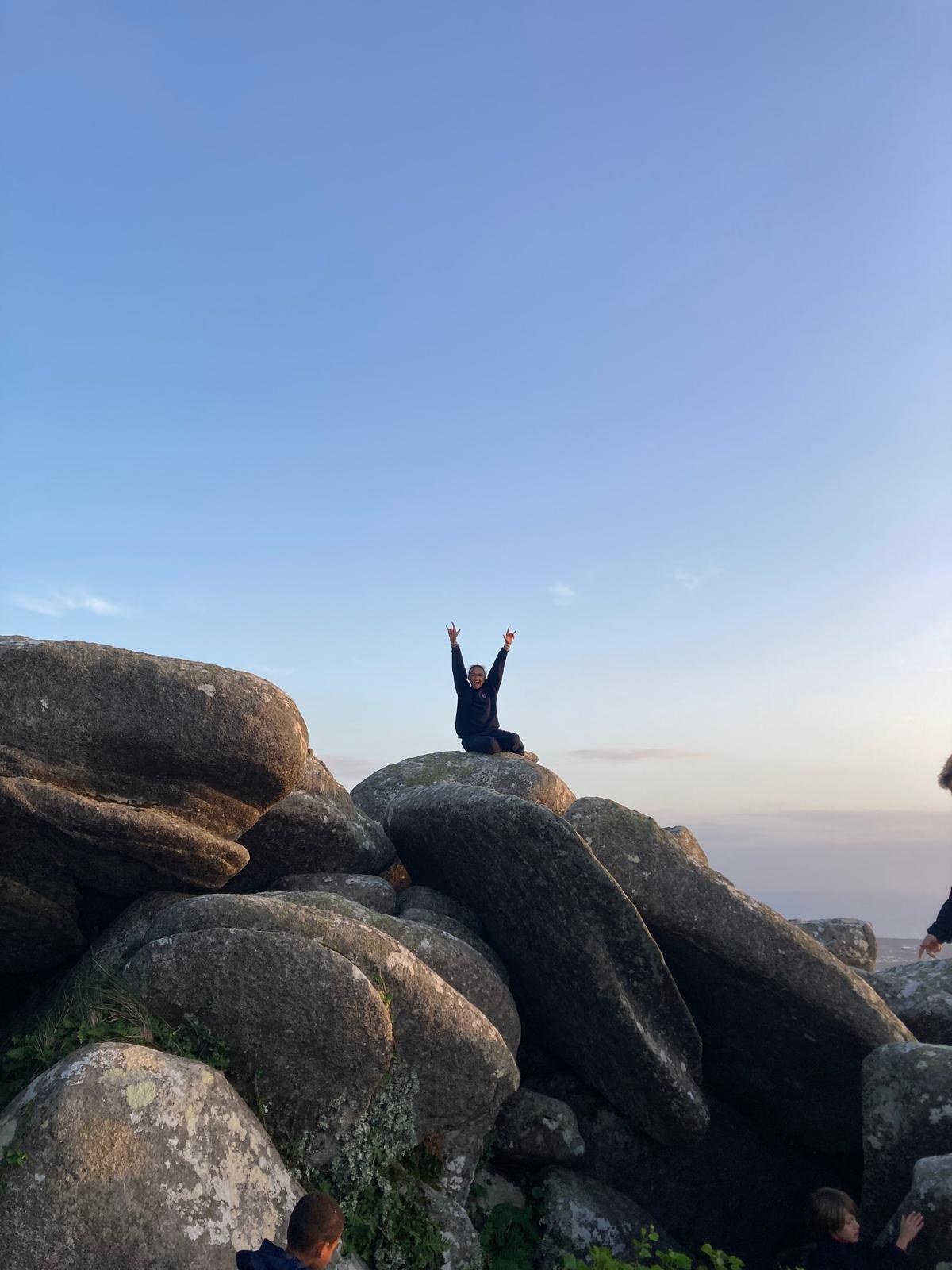 Woman celebrating on rocks at sunset during a hike near Cascais