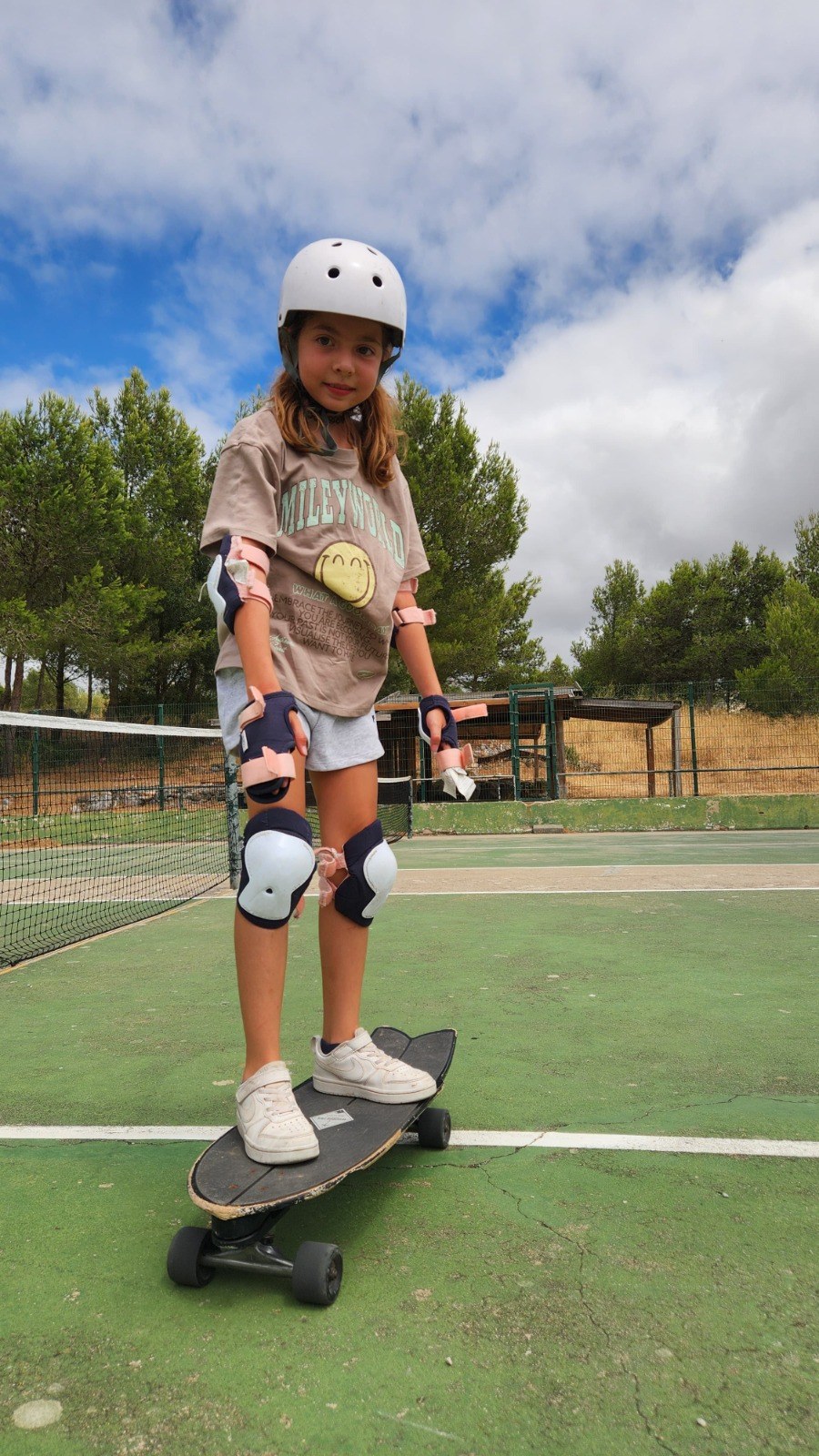 Girl in pads and helmet riding a surfskate on a sports court
