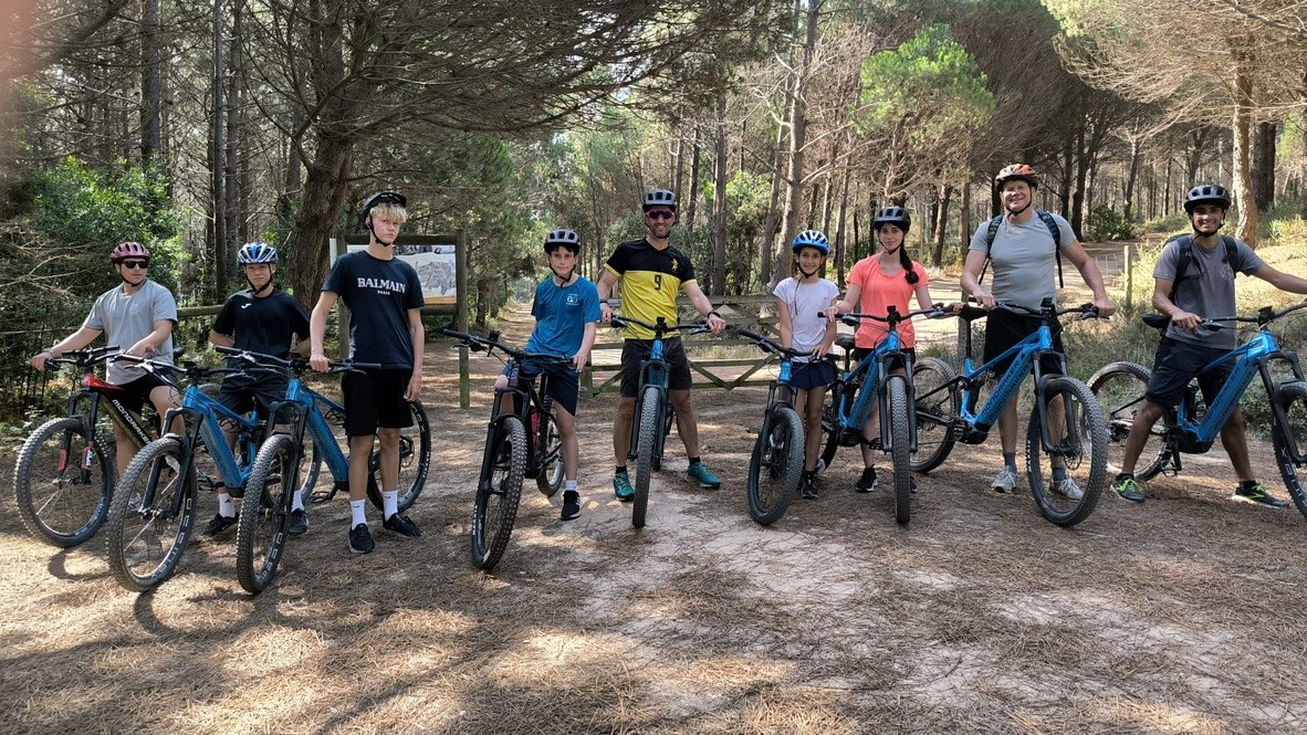 A group of adults and teenagers with e-bikes on a forest trail