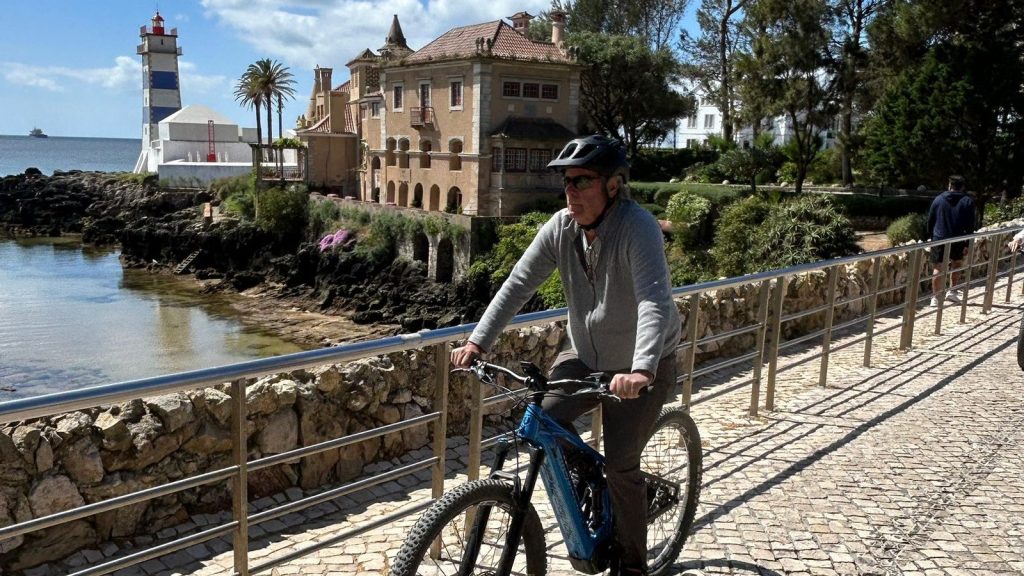 E-bike rider on the Cascais seafront with Santa Marta lighthouse behind